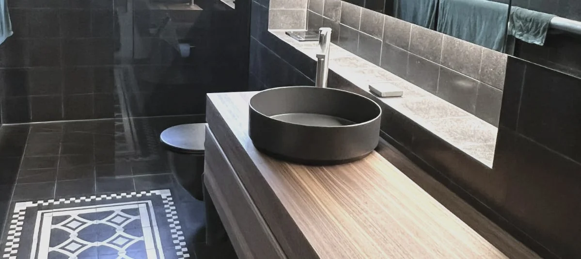 Elegantes Bad mit Glasabtrennung, Waschtisch und modernen Sanitärinstallationen.