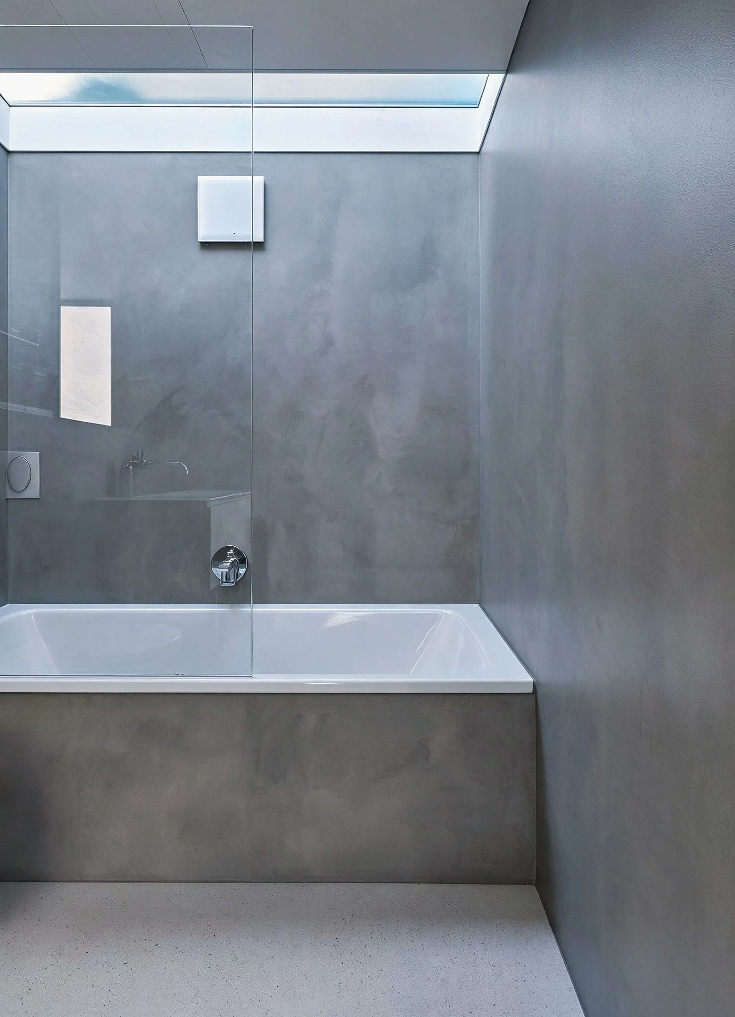 Eingebaute Badewanne mit Armatur und Natursteinwand unter einem Dachfenster.